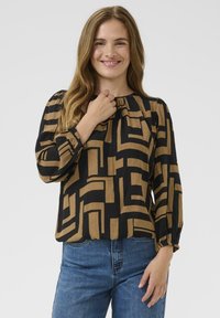 Black and gold blouse with a geometric pattern, featuring long sleeves and a gathered neckline. Made from textured fabric.
