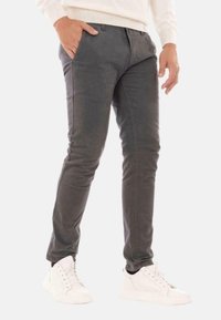 Pantaloni grigi slim-fit realizzati in tessuto misto cotone, con tasche anteriori e una texture liscia, abbinati a sneakers bianche.