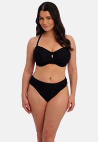 Černý bikini set se strukturovaným bandeau topem se středovým uzlem a zlatým akcentem, spárovaný s kalhotkami s vysokým pasem.