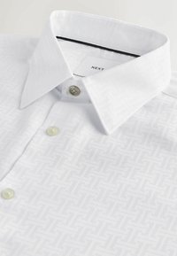 Weißes Hemd mit subtilen geometrischen Mustern, Knopfverschluss und strukturierter Kragen. Aus strukturiertem Stoff, gekennzeichnet mit "NEXT".