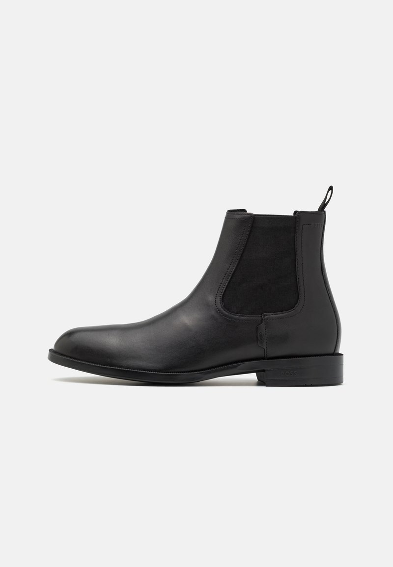 Black leather chelsea boot with elastic side panels, sleek design, rounded toe, and pull tab. Smooth texture and low stacked heel.