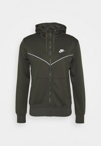 Felpa con zip verde scuro realizzata in materiale morbido. Presenta una tasca anteriore, un cappuccio regolabile con cordino e un logo Nike bianco sul petto.