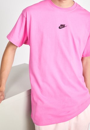Lyserød bomulds-T-shirt med rund hals, korte ærmer og et lille sort Nike-logo på brystet. Glat tekstur, afslappet pasform.