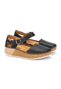 Zapatos de cuero negro con una entresuela de corcho, que presentan un diseño ondulado, correa ajustable en el tobillo y costuras contrastantes.