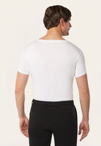 Witte t-shirt met korte mouwen en een ronde hals, gecombineerd met zwarte broek, met een gladde textuur en een getailleerd ontwerp vanuit de achteraanzicht.