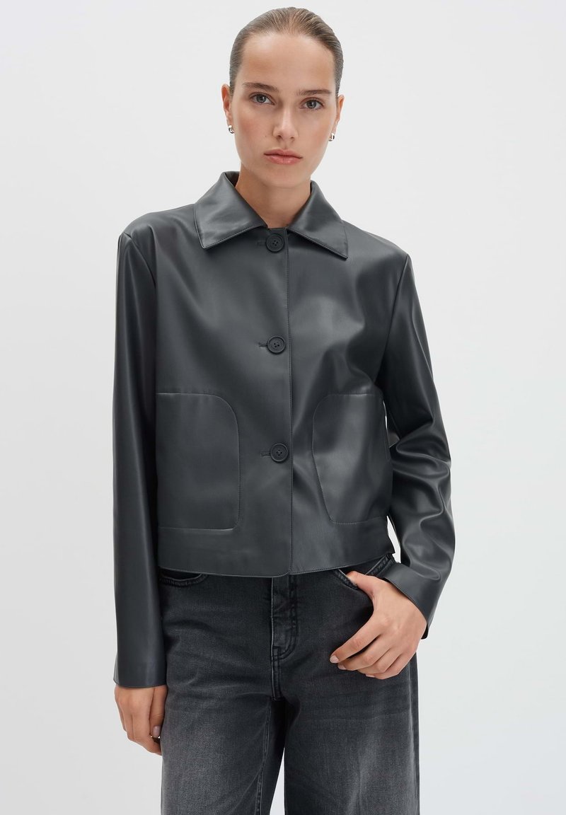 Abgeschnittene schwarze Kunstlederjacke mit spitzem Kragen, sechsknöpfigem Verschluss und zwei Fronttaschen. Glatte Textur mit eleganter Oberfläche.
