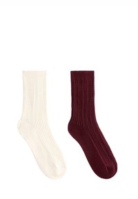 To par ribstrikkede sokker: den ene i off-white og den anden i mørk burgunder. Begge har et blødt, elastisk stof og afrundede tæer.