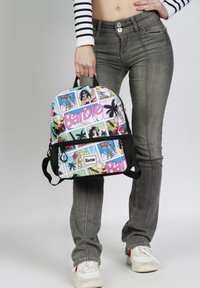 Mochila con temática de Barbie, con un estampado de estilo cómic multicolor, material de tela, forma redondeada, detalles de malla negra y bolsillo con cremallera en la parte frontal.