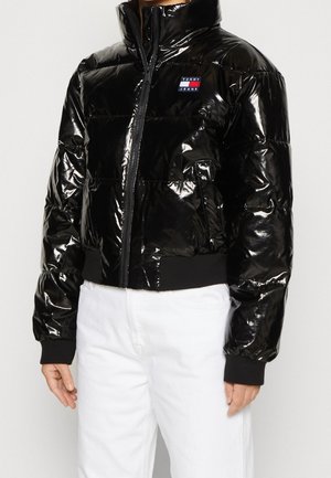 Sort pufferjakke med en blank finish, høj krave, lynlås foran, ribbede manchetter og talje. Har et lille Tommy Jeans-logo patch.