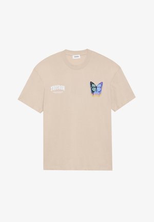Beige cotton t-shirt featuring a small graphic of a blue butterfly with black accents and a drip design, along with white text on the left side.