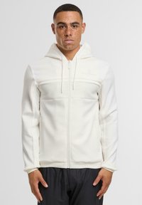 Felpa bianca con zip, dotata di una sezione centrale testurizzata, tessuto morbido, cappuccio e cordoncino. Le maniche lisce e un design aderente completano l'aspetto.