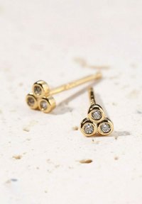 Goldene Steckerohrringe mit einem dreieckigen Design und drei runden Fassungen, die jeweils einen kleinen, klaren Stein halten. Glatte, polierte Oberfläche.