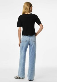 Melna īsām piedurknēm tops, kombinēts ar gaiši ziliem augstvērtīgiem platām biksēm un melnbaltām svītrainām čībām. Gluda auduma, brīvāka piegriezuma.