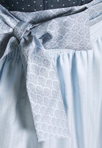 Vêtement bleu clair avec tissu froncé, doté d'une ceinture en tissu à motifs dans des tons bleu foncé et gris à motif floral.