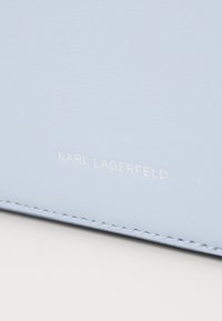 Světle modrá kožená peněženka s hladkým povrchem a bílým embosovaným logem "KARL LAGERFELD", doplněná o ladící prošití.