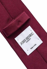 Burgundin väriin kuuluva solmio, jossa on teksturoitu, vinoraitakuosis. Vahvistettu valkoinen etiketti, jossa lukee "JOHN HENRIC SWEDEN" ja "Valmistettu Italiassa".