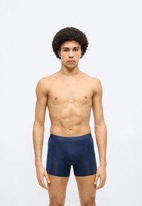 Μπλε ναυτικό βαμβακερό μποξεράκι με ελαστική μέση, διαθέτει λεία υφή και εφαρμοστή σχεδίαση. Χωρίς εμφανή σχέδια ή διακοσμητικά στοιχεία.