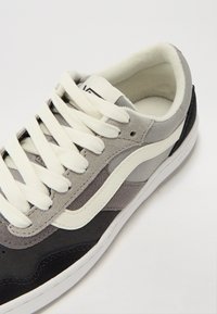 Gray and black suede sneaker with white laces and a cream outsole. Features a classic design and contrasting side stripe.