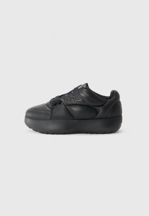 Schwarzer Sneaker mit einem glatten Lederoberteil, runder Zehenpartie, niedrigem Design, strukturierten Akzenten und einer dicken gepolsterten Sohle.