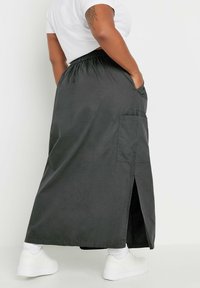 Pitkä tummanharmaa hame, jossa on joustava vyötärö, sivutasku ja etuhalkio. Yhdistettynä valkoisiin tennareihin ja nilkkasukkia.