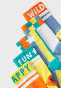 Bunte Baumwollsocken in einem Winkel angeordnet, mit auffälligem Text an den Bündchen: "WILD," "SPASS," "GLÜCKLICH" und Sternmustern in lebhaften Farben.