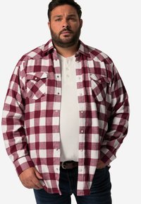 Rød og hvid ternet flannel skjorte med to brystlommer, knaplukning foran og blød tekstur, båret over en lys grå henley skjorte.