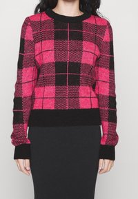 Rosa-schwarz karierter Pullover mit rundem Ausschnitt, Rippbündchen an den Ärmeln und am Saum. Weiche Textur, figurbetontes Design mit markanten Karomustern.