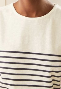 Camiseta de manga corta en algodón crema, con rayas horizontales en color marino, cuello redondo y textura suave.