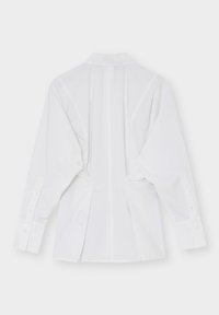 Chemise blanche à manches longues avec col et poignets boutonnés vue de dos sur un fond uni.