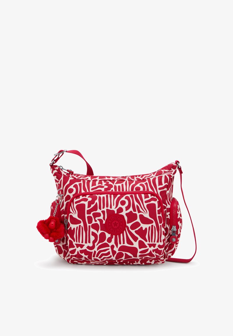 Rode en witte tas met een patroon en een gestructureerd oppervlak, voorzien van een decoratieve pompon, verstelbare riem en meerdere met ritsen afgesloten vakken.