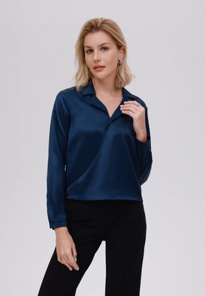 Blouse en satin bleu marine avec des manches longues, un col pointu et un design asymétrique. Comprend des poignets boutonnés et une légère brillance.