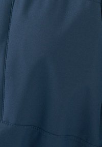 Tessuto blu navy con una consistenza liscia, caratterizzato da cuciture verticali e una leggera lucentezza. Il materiale sembra resistente e ben strutturato.