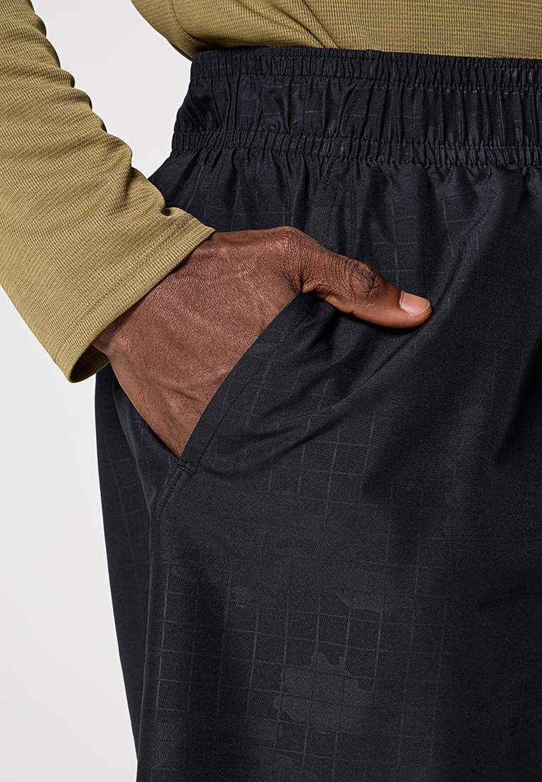 Pantalons de sport noirs, texturés, avec une coupe décontractée, dotés d'une taille élastique et d'une poche latérale, accompagnés de manches longues vert olive.