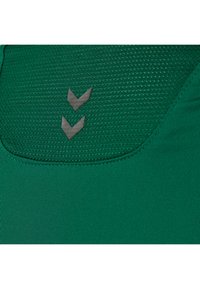 Groene sportshirt met een gestructureerd bovenste gedeelte, voorzien van twee verhoogde grijze chevron-logo-accenten onder de halslijn.