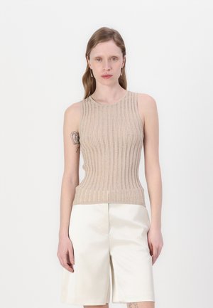 Top senza maniche a coste beige con scollatura rotonda. Realizzato in tessuto testurizzato, design aderente, abbinato a pantaloni corti bianchi strutturati.