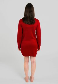 Il vestito a maglione rosso presenta maniche lunghe, un colletto rotondo e una vestibilità leggermente affusolata, che arriva a metà coscia con dettagli a coste sull'orlo.