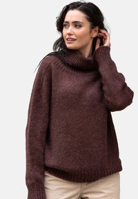 Brązowy, oversize sweter dzianinowy z golfem, prążkowymi mankietami i dołem. Miękka tekstura z lekko luźnym krojem i opadającymi ramionami.