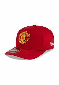 Red baseball cap with a curved brim and adjustable back. Features embroidered Manchester United logo on the front. Made from fabric.