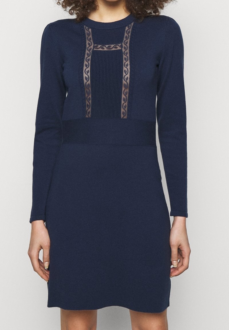 Mörkblå stickad klänning med långa ärmar, med genomskinlig mesh och ribbat detaljer på bodice, samt en åtsittande midja.