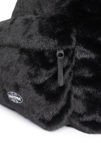 Schwarze Kunstfelltasche mit einer weichen Textur, ausgestattet mit einem robusten Reißverschluss und einem strukturierten Tragegurt. Enthält ein rundes Eastpak-Logo. 