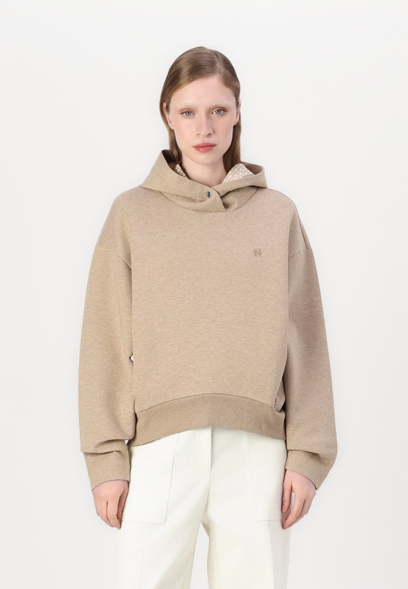 Felpa oversize beige con cappuccio regolabile e polsini a costine. Presenta un logo discreto e un rivestimento decorato all'collo.