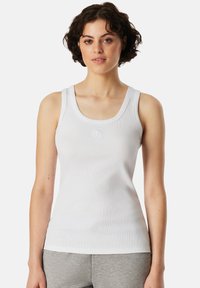 White ribbed tank top with a round neckline and wide straps, featuring a small embroidered logo at the center. Material appears soft and stretchy.