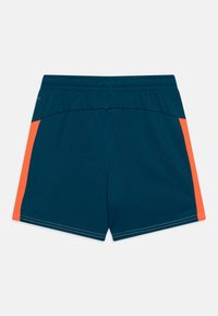 Bermudas deportivas para hombre en azul marino con paneles laterales naranjas. Cuentan con una cinturilla elástica y una textura suave. No tienen bolsillos visibles.