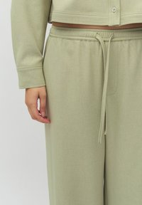 Lichtgroene, verkorte trui met een zachte textuur en zichtbare stiksels, gecombineerd met bijpassende broek met elastische tailleband en een trekkoord.