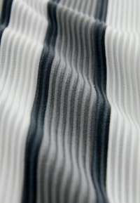 Textile fabric with alternating vertical stripes in white, gray, and dark gray. The texture is ribbed, showing depth and layers.