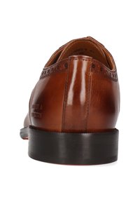 Chaussure habillée en cuir marron avec semelle noire, détails de brogue près du talon, vue de dos sur fond blanc.