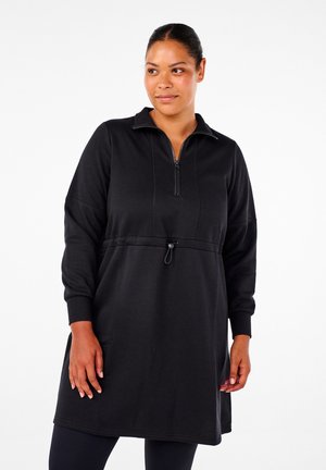 Must kattega musta dressi pehmes kangas. Sellel on vöökoht, mille saab reguleerida nööriga, pikad varrukad ja sportlik kaeluse disain.