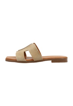 Sandalia slide de ante beige con cortes cuadrados abiertos, suela plana marrón y tacón bajo, diseñada para uso casual.