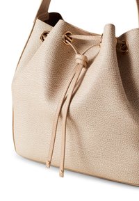 Beige textured leather bucket bag with gold hardware, featuring a drawstring closure and two long leather ties.