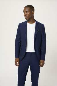 Traje navy con un corte ajustado, que presenta solapas elegantes, un pañuelo de bolsillo y una camiseta blanca por debajo. Textura suave, detalles de diseño sutiles.